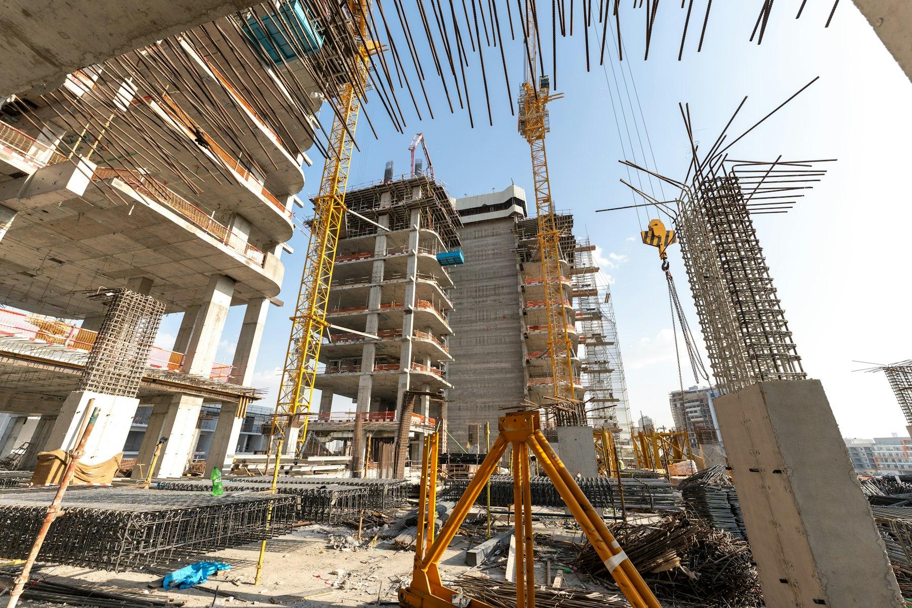 High-rise buildings under construction with exposed rebar and cranes